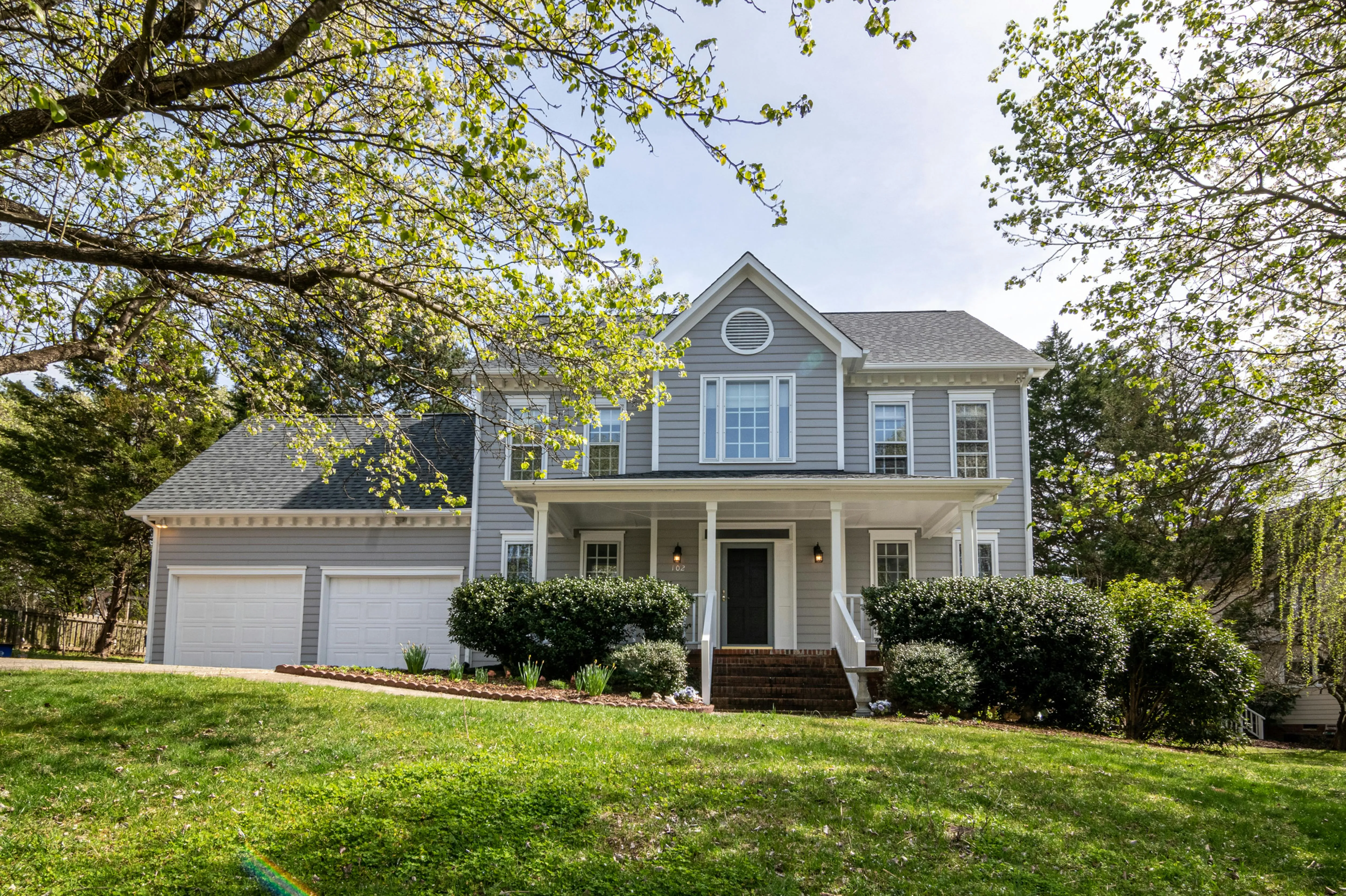 Two-story colonial home with blue-gray siding and new gray asphalt shingle roof, featuring a covered front porch