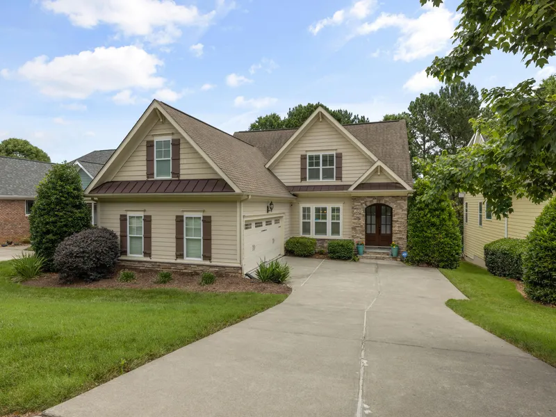 Craftsman-style home with tan siding, stone accents, and newly installed brown metal accent roofing over the garage