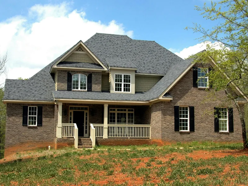 Brick two-story colonial home with new gray architectural shingles and white front porch, completed residential roof replacement